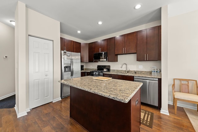 kitchen featuring baseboards, a kitchen island, stainless steel appliances, and dark wood-type flooring