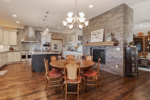 14431 E 2400 N Rd, Hudson, IL 61748 - dining room featuring dark wood-style flooring, a stone fireplace, ornamental molding, recessed lighting, and a chandelier