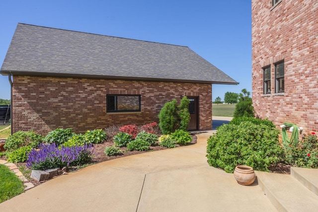 14431 E 2400 N Rd, Hudson, IL 61748 - view of home's exterior with a shingled roof, a patio, and brick siding