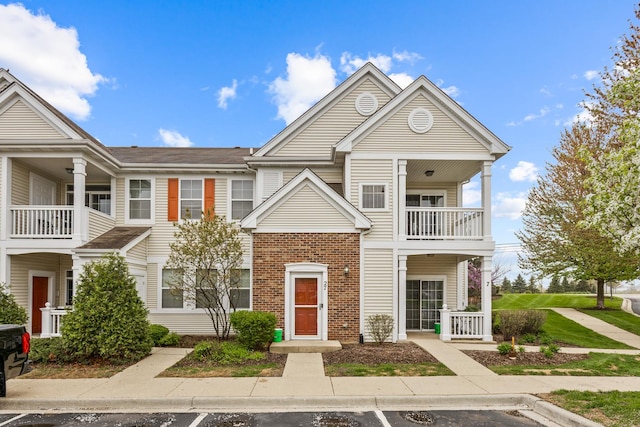 townhome / multi-family property with uncovered parking, brick siding, and a balcony