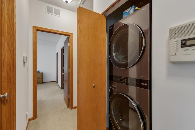 laundry room with stacked washer and clothes dryer, laundry area, visible vents, baseboards, and light colored carpet