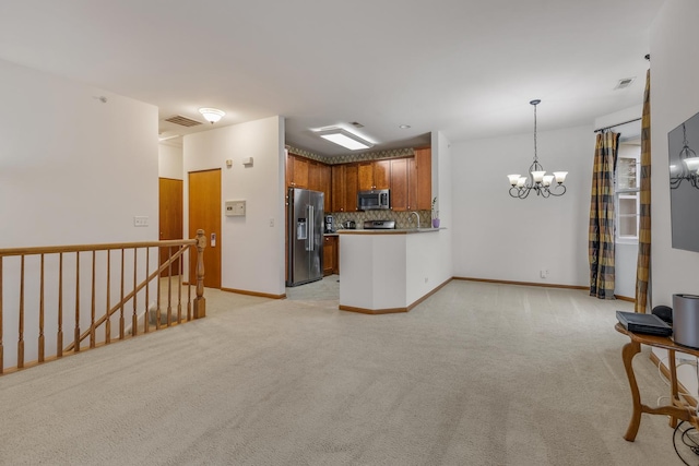 kitchen featuring an inviting chandelier, stainless steel appliances, tasteful backsplash, and light carpet