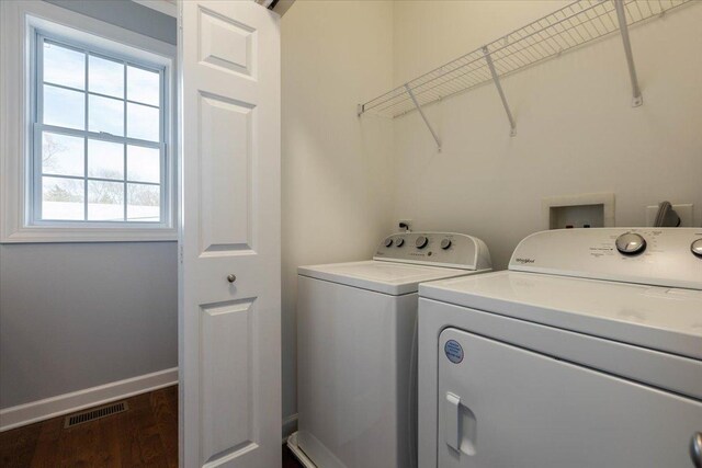 laundry area with dark wood-style flooring, baseboards, visible vents, separate washer and dryer, and laundry area
