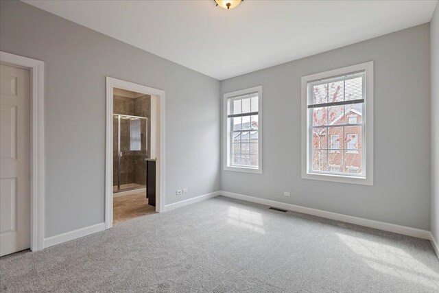 unfurnished bedroom with ensuite bath, visible vents, carpet flooring, and baseboards