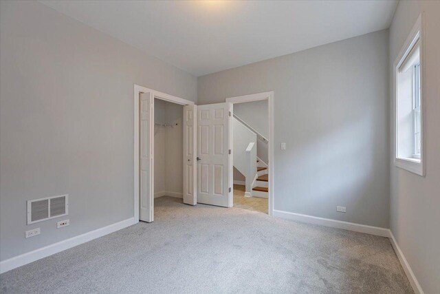 unfurnished bedroom with light carpet, a closet, visible vents, and baseboards