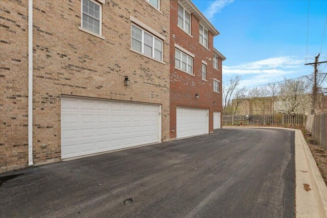 garage featuring aphalt driveway and fence