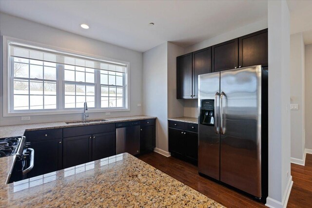 kitchen featuring dark wood finished floors, appliances with stainless steel finishes, baseboards, and a sink