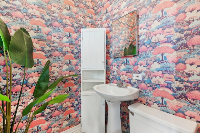 half bath with toilet and wallpapered walls