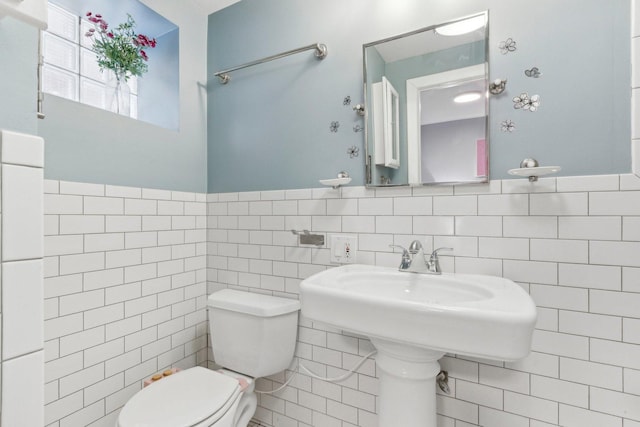 bathroom featuring toilet, tile walls, and a wainscoted wall