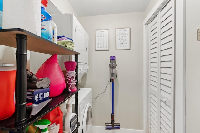 clothes washing area with baseboards, laundry area, and stacked washer / drying machine