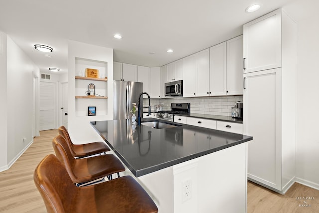 kitchen featuring open shelves, dark countertops, light wood-style flooring, appliances with stainless steel finishes, and white cabinetry