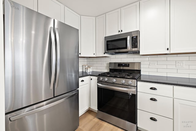 kitchen featuring dark countertops, light wood-type flooring, white cabinetry, and stainless steel appliances