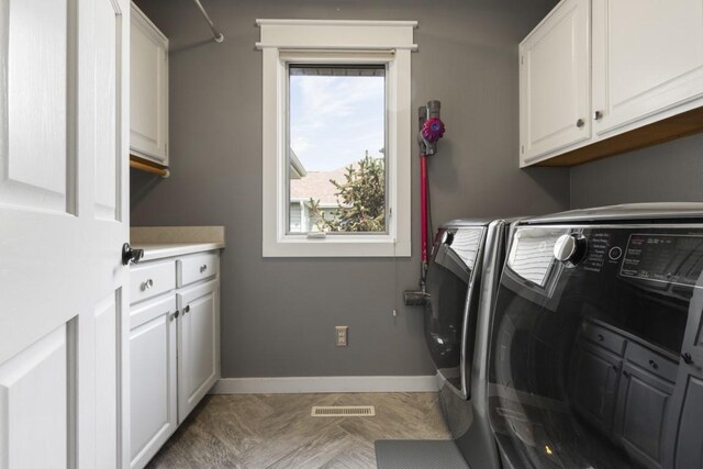 clothes washing area featuring cabinet space, washing machine and dryer, visible vents, and baseboards