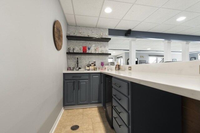 bar with a sink, a drop ceiling, baseboards, decorative backsplash, and indoor wet bar