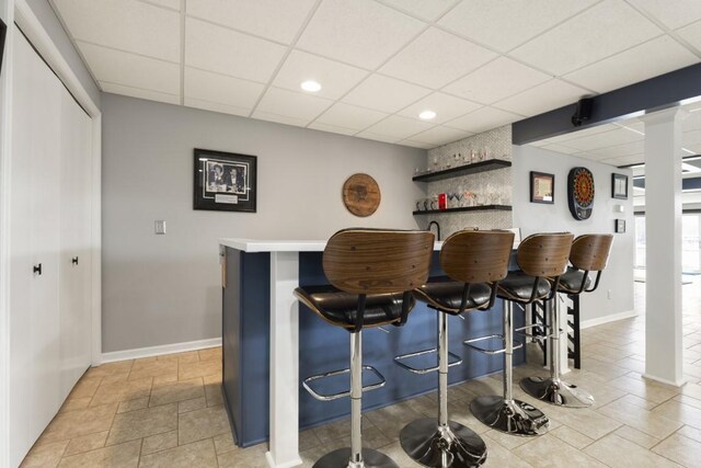 bar with indoor wet bar, baseboards, a paneled ceiling, and recessed lighting