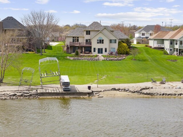 back of house featuring a lawn and a water view