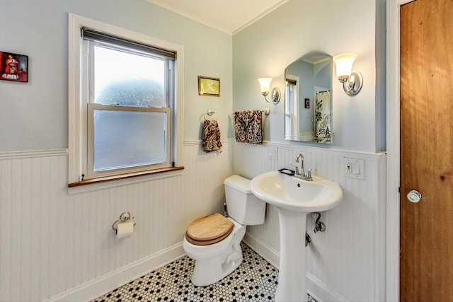 full bath with a wainscoted wall, a sink, tile patterned flooring, and toilet