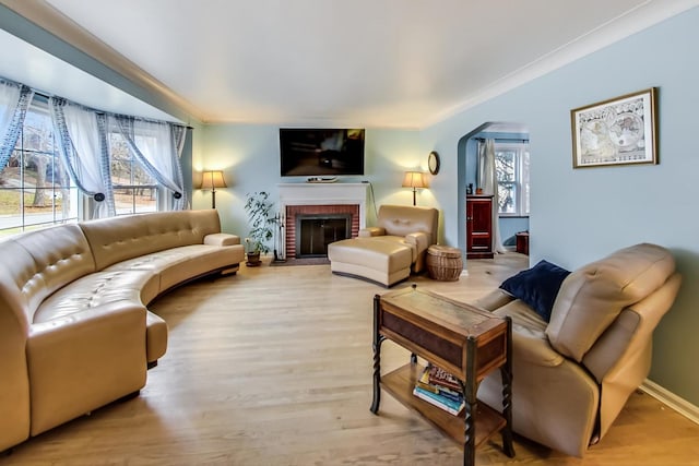 living room with arched walkways, light wood-style floors, and a healthy amount of sunlight