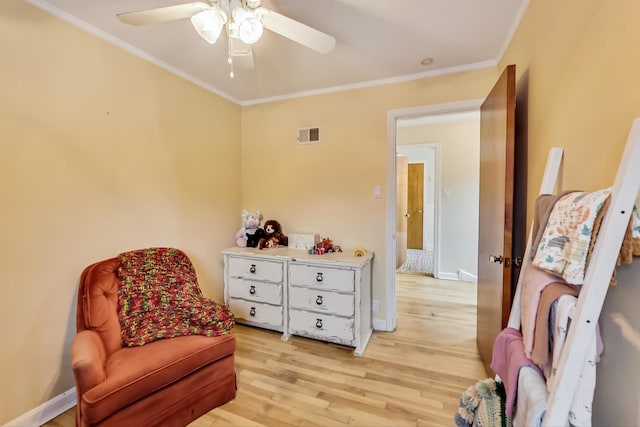 sitting room with crown molding, a ceiling fan, visible vents, and light wood-style flooring