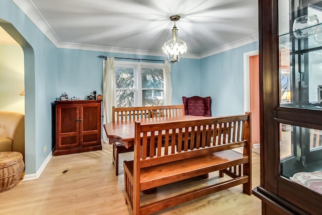 dining area featuring an inviting chandelier, arched walkways, light wood-style floors, crown molding, and baseboards