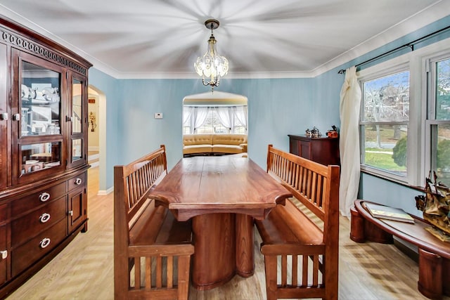 dining room with arched walkways, a wealth of natural light, a notable chandelier, and light wood-style floors