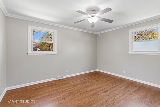 spare room featuring baseboards, visible vents, wood finished floors, and crown molding