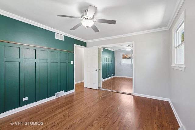 unfurnished bedroom featuring wood finished floors, visible vents, a ceiling fan, and ornamental molding