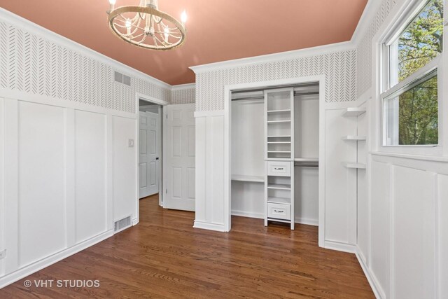 unfurnished bedroom featuring crown molding, visible vents, wallpapered walls, an inviting chandelier, and a decorative wall