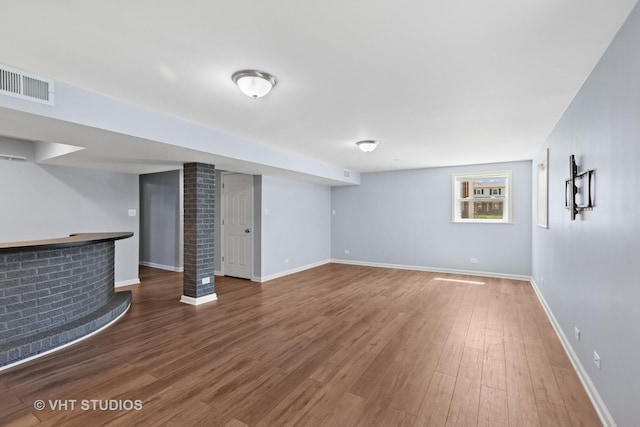 basement featuring a dry bar, wood finished floors, visible vents, and baseboards