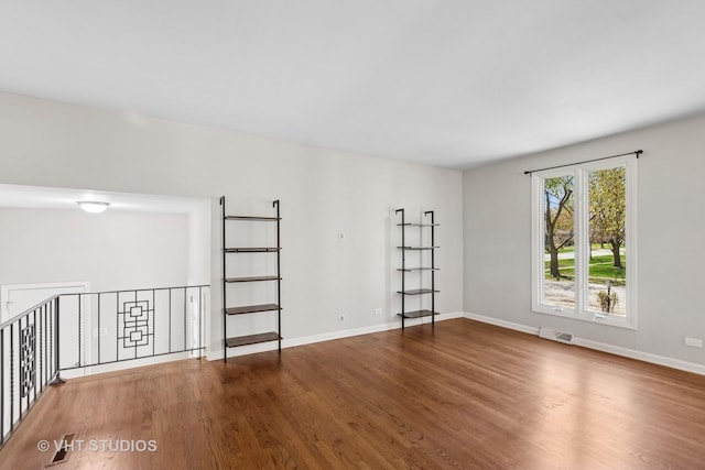 unfurnished room with visible vents, wood finished floors, and baseboards