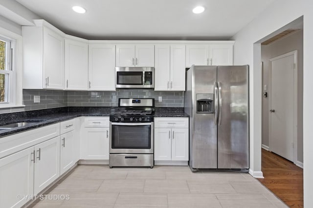 kitchen featuring dark stone counters, recessed lighting, tasteful backsplash, white cabinets, and appliances with stainless steel finishes