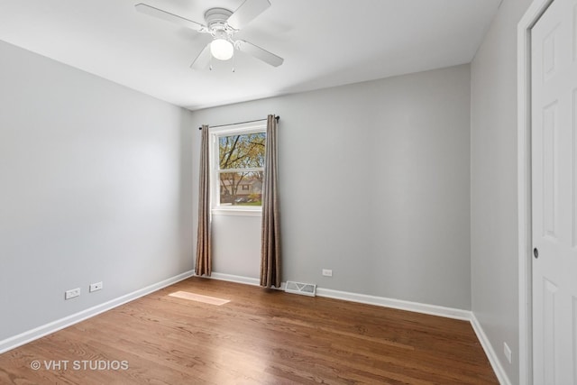 unfurnished room with a ceiling fan, visible vents, wood finished floors, and baseboards