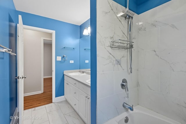 full bath with bathing tub / shower combination, double vanity, marble finish floor, a sink, and baseboards