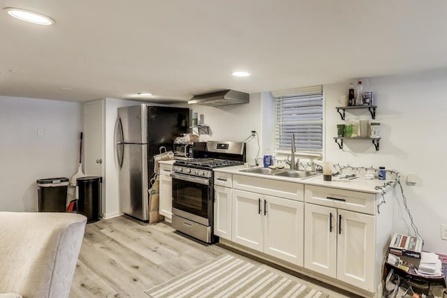 kitchen featuring light wood-style flooring, white cabinetry, wall chimney exhaust hood, light countertops, and appliances with stainless steel finishes