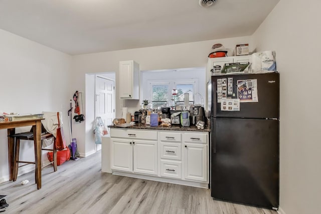 kitchen featuring freestanding refrigerator, visible vents, light wood finished floors, and white cabinets