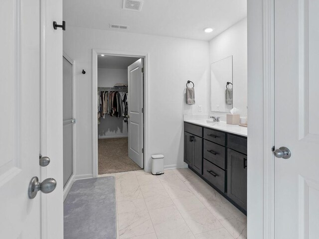bathroom featuring visible vents, marble finish floor, vanity, and a walk in closet