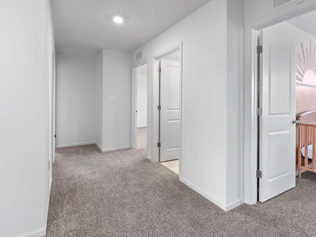 corridor with baseboards, visible vents, and carpet