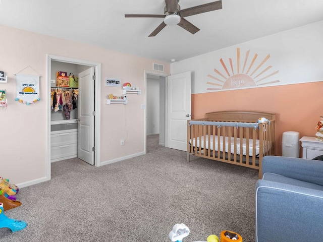 bedroom with baseboards, visible vents, carpet, and a walk in closet