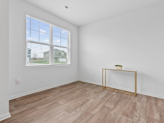 unfurnished room with wood finished floors, visible vents, and baseboards
