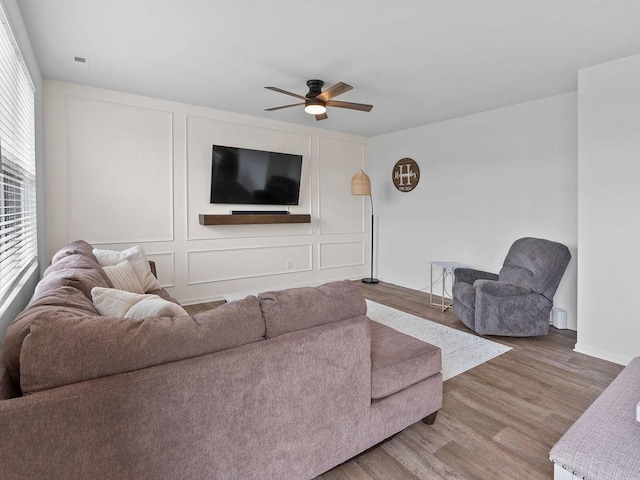 living area with baseboards, a ceiling fan, and wood finished floors