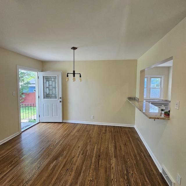 unfurnished dining area featuring dark wood-type flooring, baseboards, and healthy amount of natural light