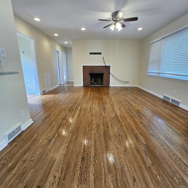 unfurnished living room with a brick fireplace, a ceiling fan, wood finished floors, baseboards, and recessed lighting