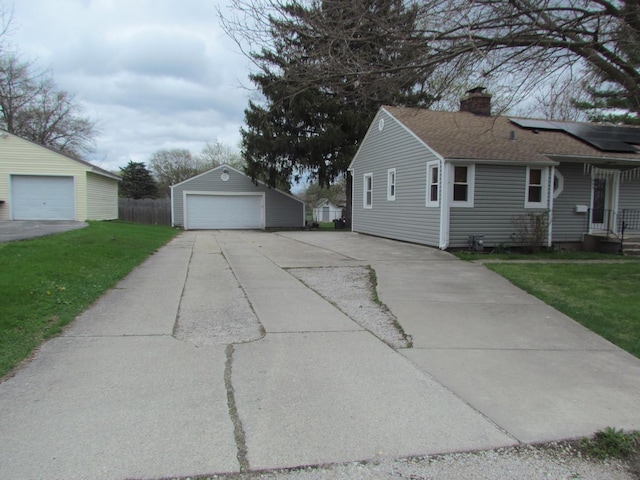 view of side of home featuring a chimney, an outbuilding, a detached garage, and roof with shingles