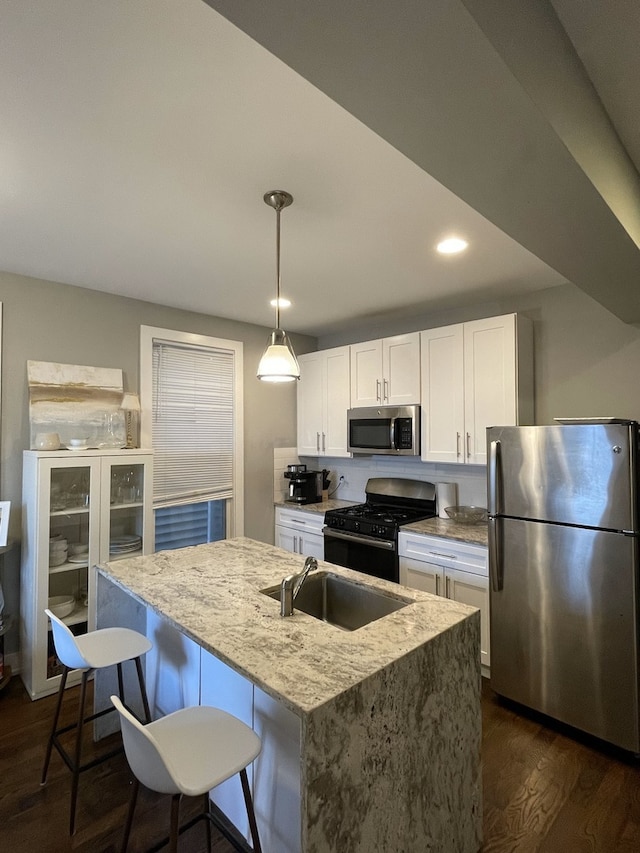 1941 W Roscoe St, Chicago, IL 60657 - kitchen with light stone counters, a sink, appliances with stainless steel finishes, white cabinets, and dark wood-style flooring