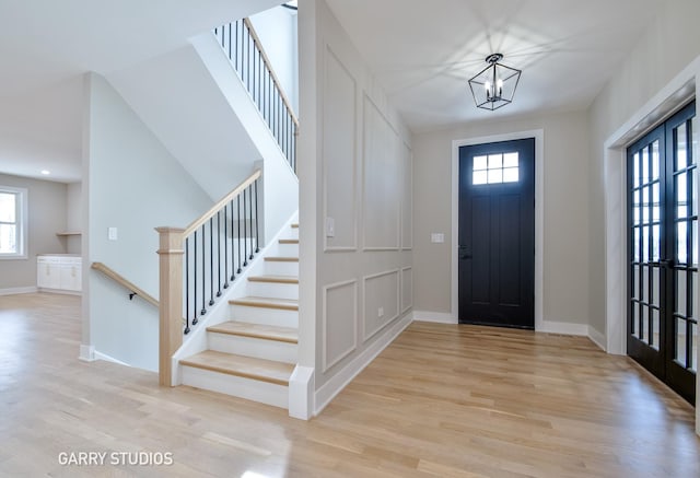foyer with stairs, a notable chandelier, wood finished floors, and baseboards