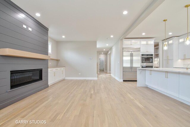 unfurnished living room with a fireplace, light wood-type flooring, baseboards, and recessed lighting