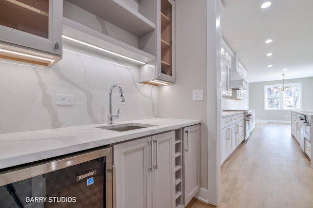 kitchen featuring a sink, recessed lighting, glass insert cabinets, open shelves, and beverage cooler