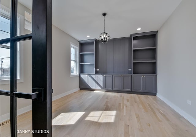 unfurnished dining area with light wood finished floors, baseboards, an inviting chandelier, and recessed lighting