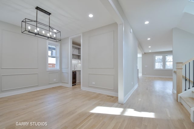 unfurnished dining area featuring light wood-type flooring, visible vents, recessed lighting, a notable chandelier, and stairway
