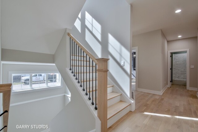 stairs with baseboards, wood finished floors, and recessed lighting